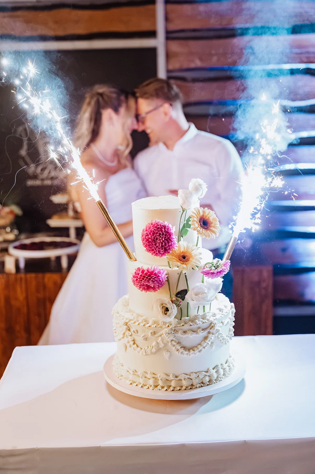 A pár csillagszóró mellett áll az esküvői torta mögött a Nairamban.