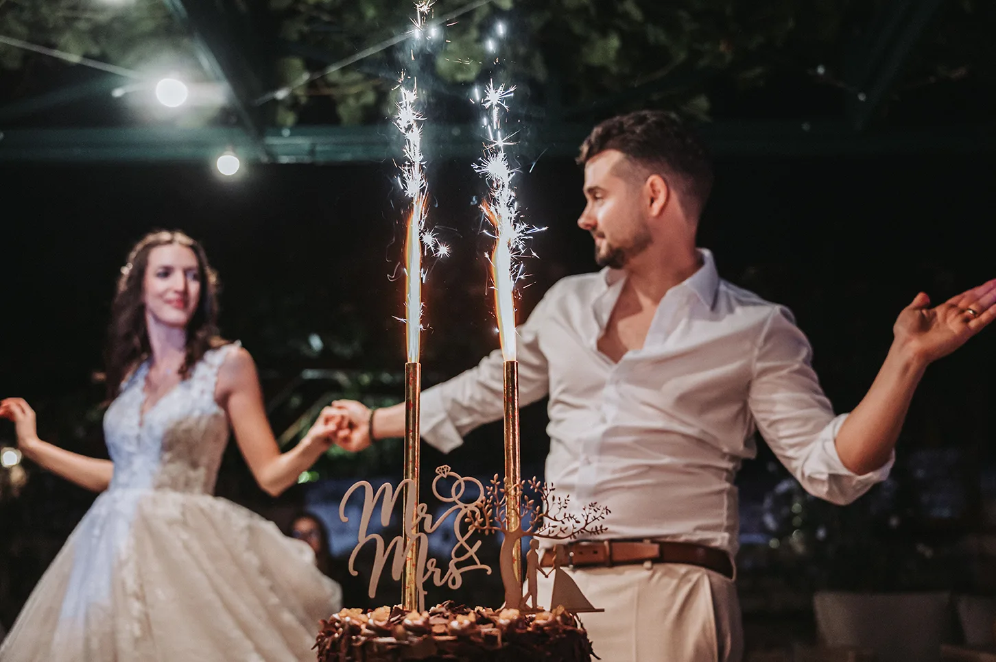 A vőlegény szikraszökőkút mellett táncol a Debreczeni Pincénél, mögötte a menyasszonnyal